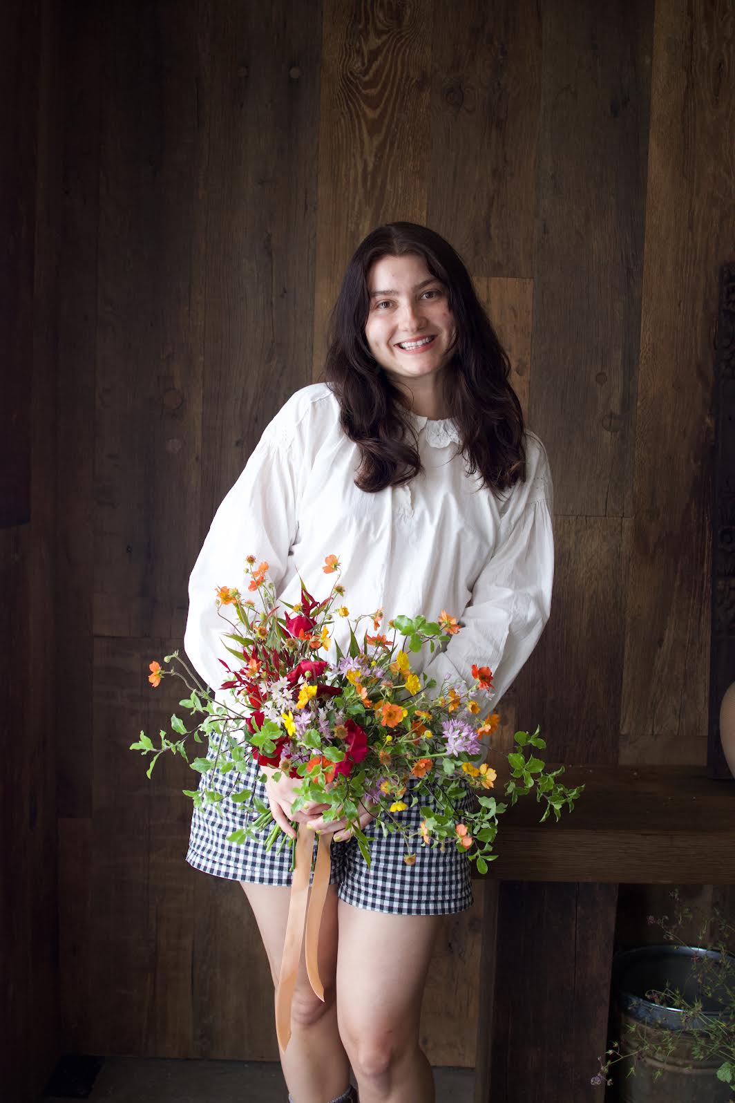 Woman holding a bouquet of flowers against a wooden background