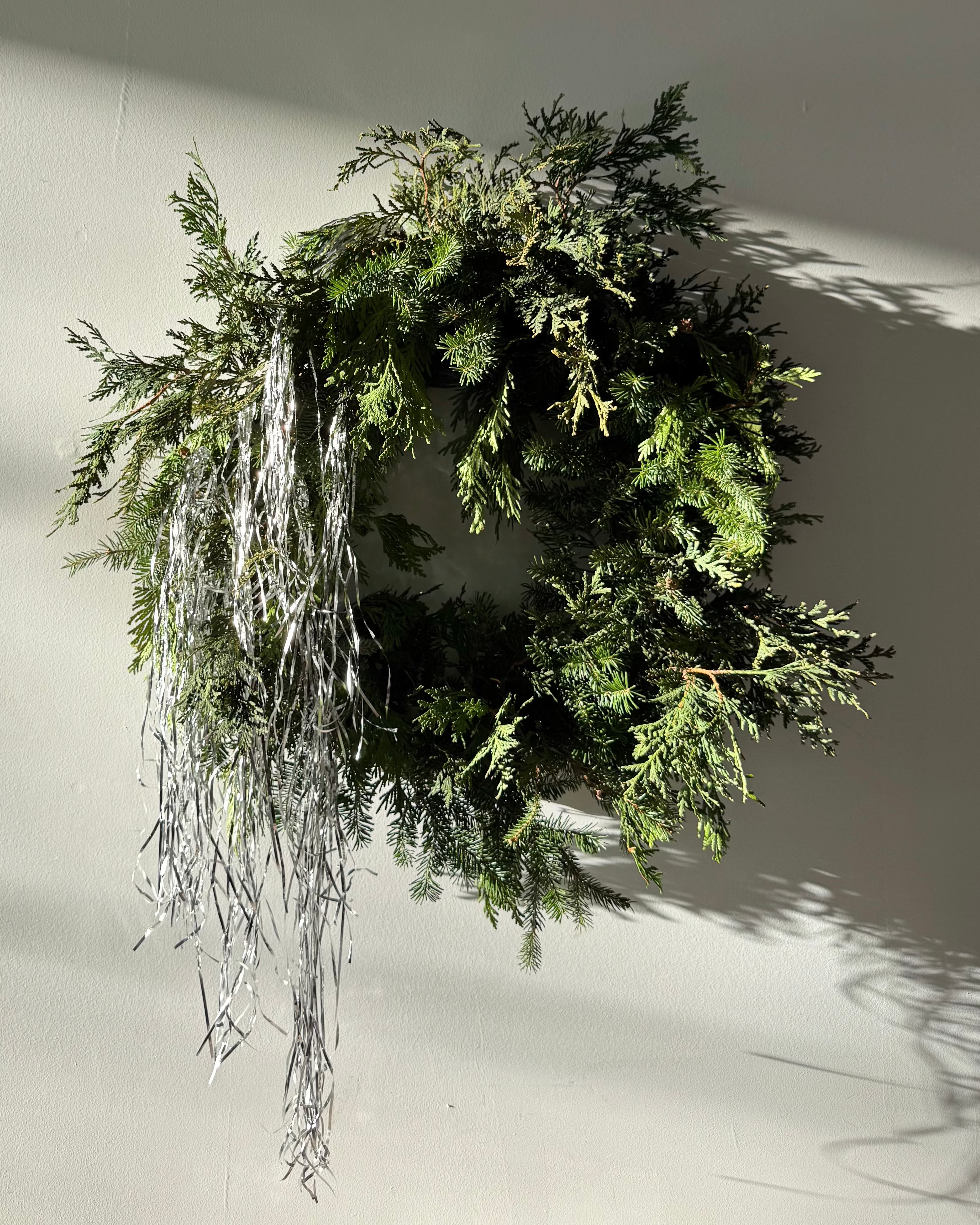 Evergreen wreath with tinsel on a white wall
