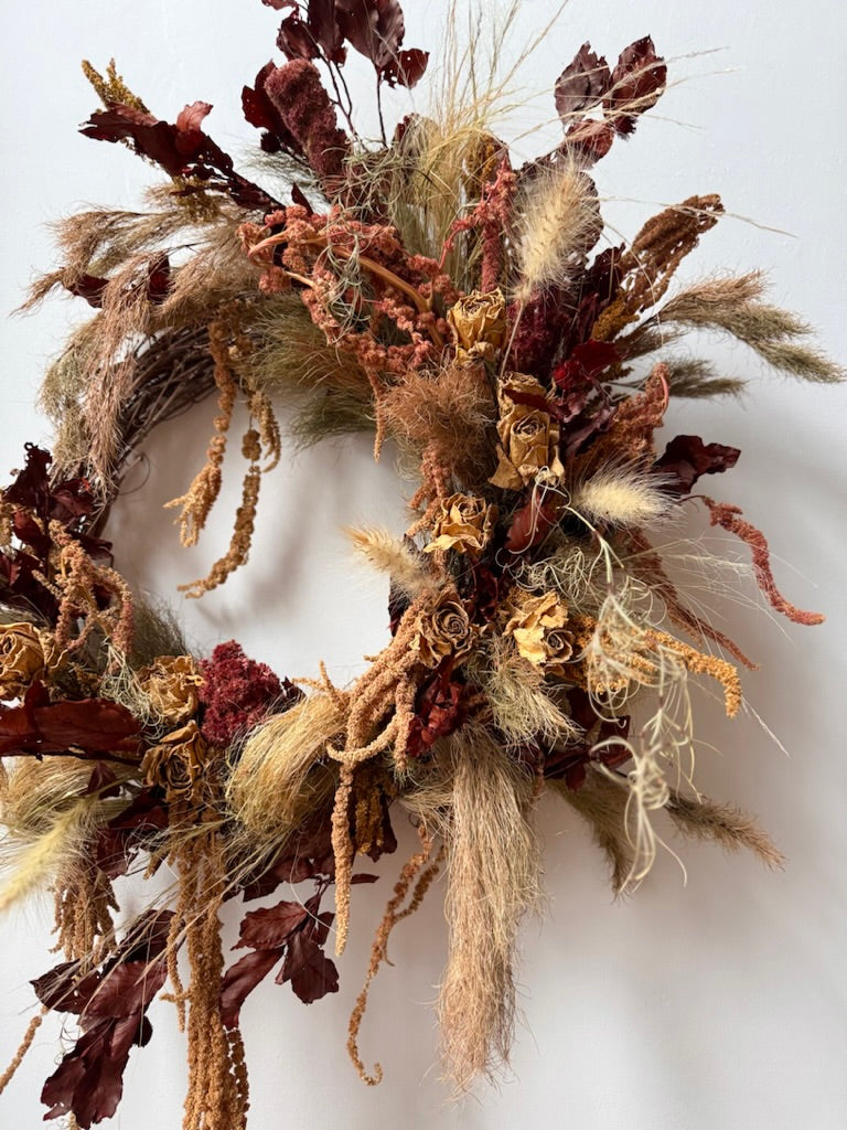 Decorative wreath with dried leaves and grasses on a white background