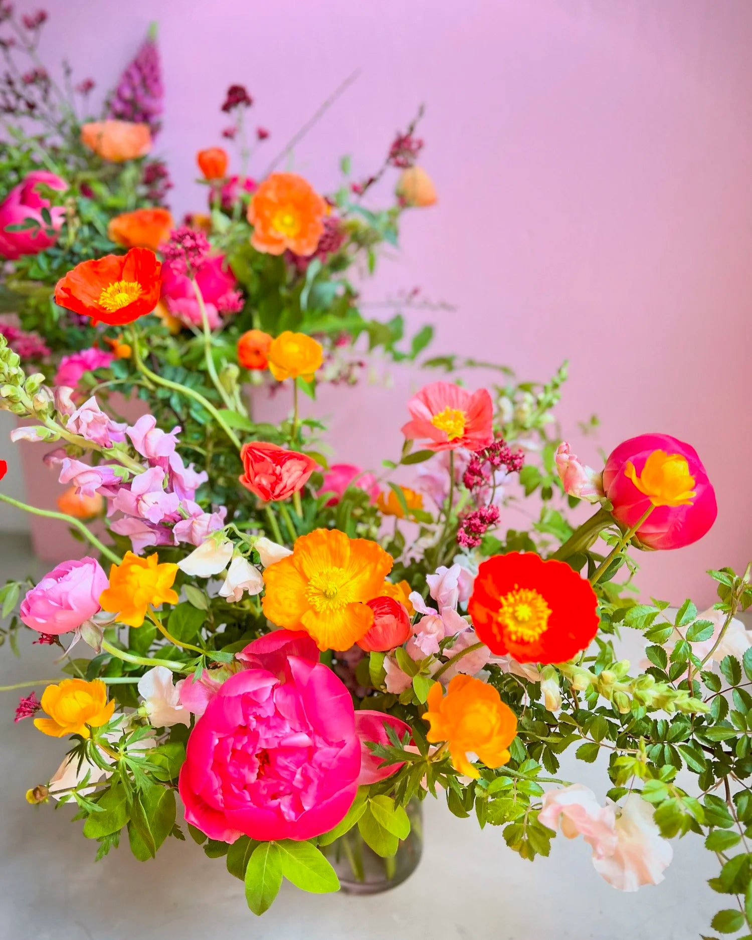 Colorful flower arrangement with pink, orange, and yellow flowers on a light background