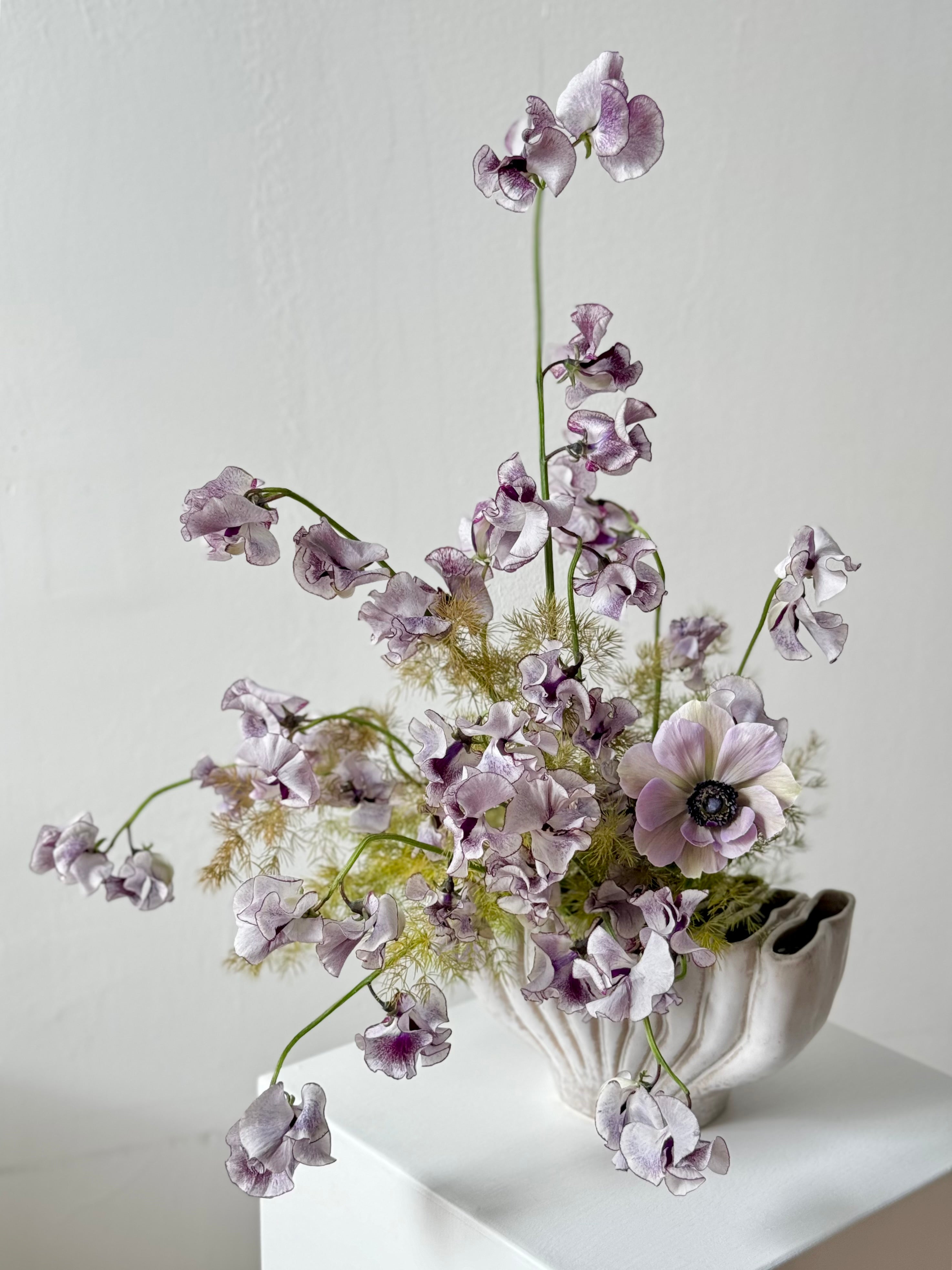 portland maine florist created sympathy flower arrangement of purple sweet peas and anenomes in a shell vase
