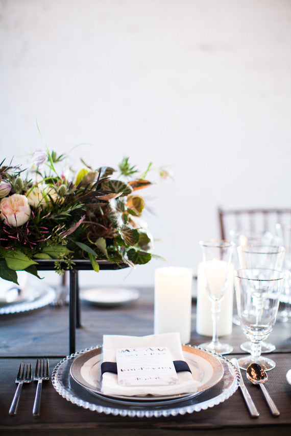 Elegant table setting with floral centerpiece, candles, and cutlery on a white background