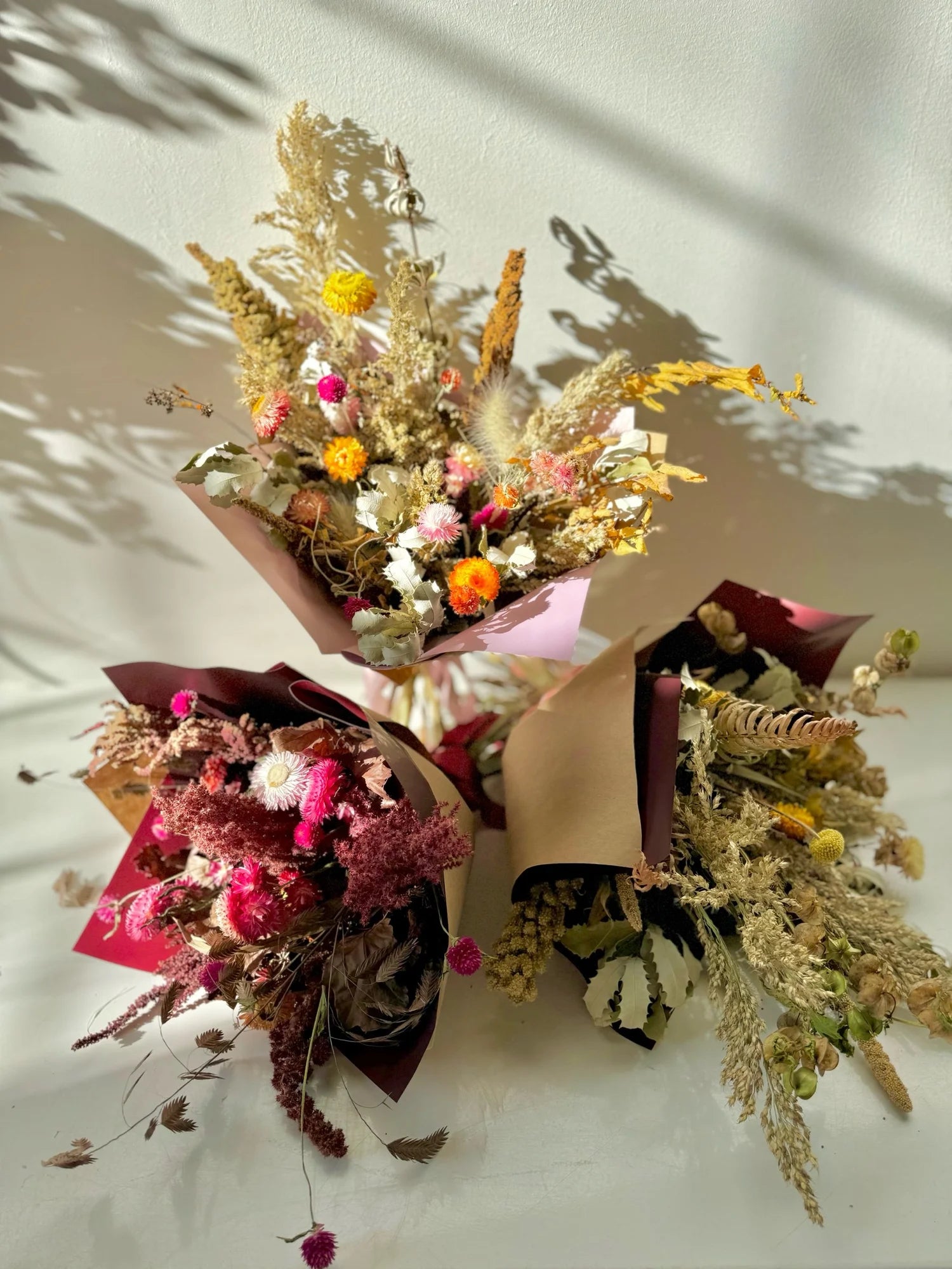 Three dried flower bouquets on a light background