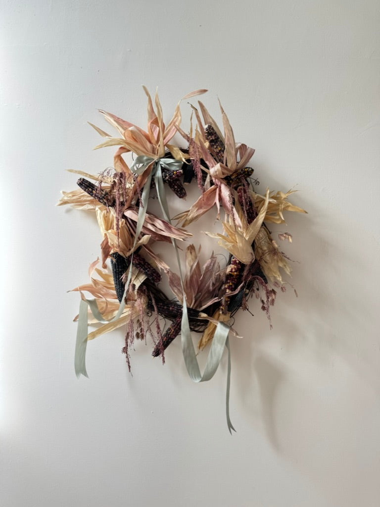 Decorative wreath with dried flowers and leaves on a plain background