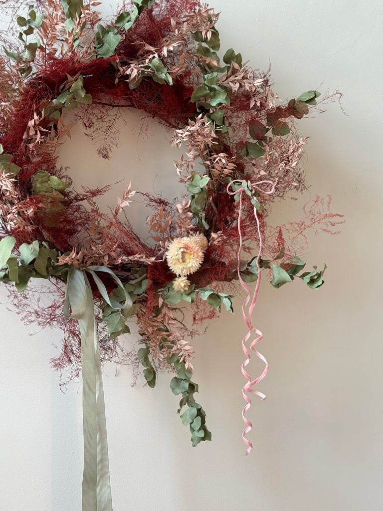 Decorative wreath with greenery and ribbons on a white background