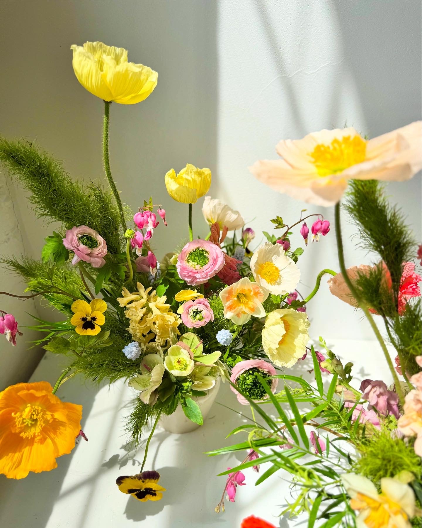 Colorful flower arrangement with yellow, pink, and green flowers on a white surface.