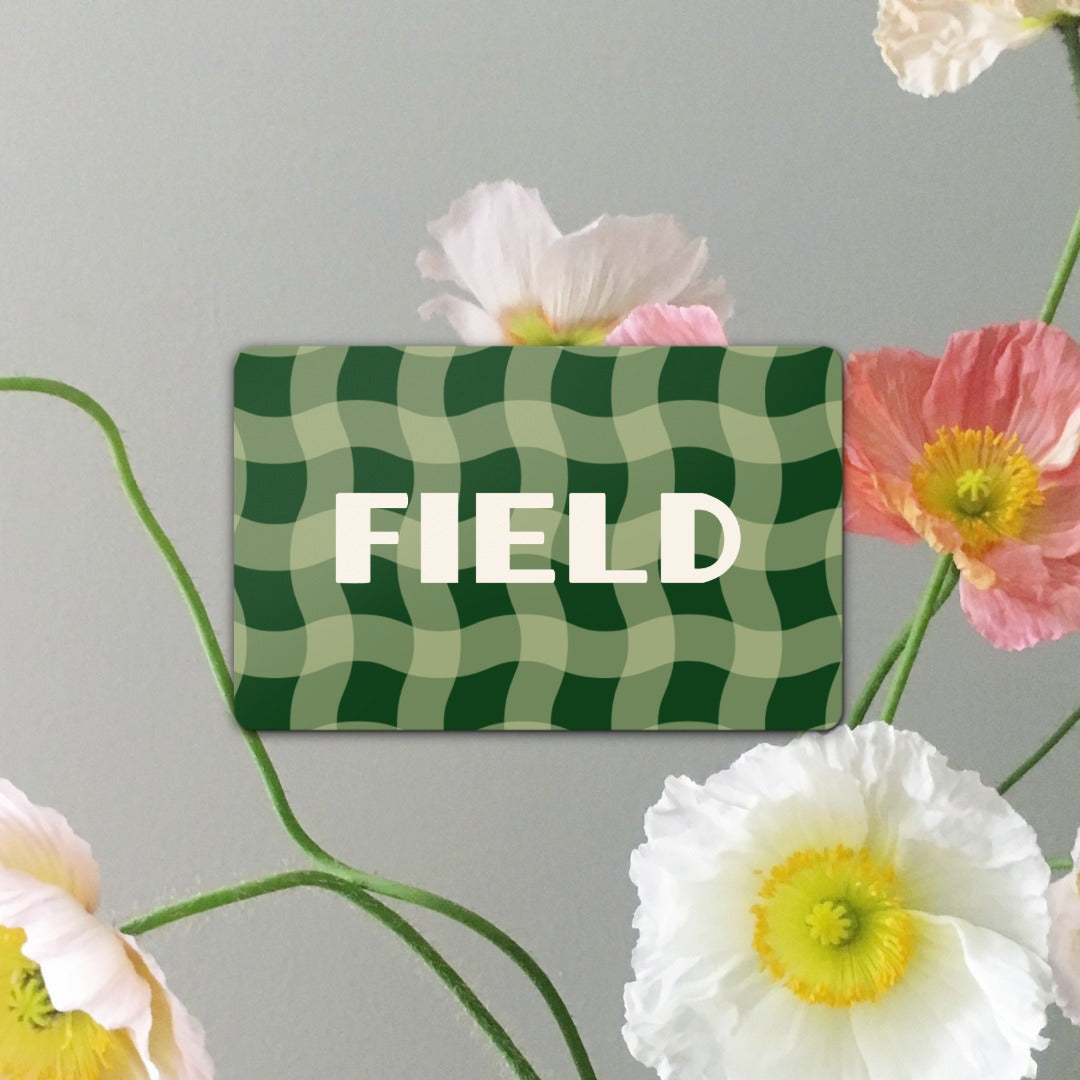 Green checkered gift card with 'FIELD' text surrounded by flowers on a light gray background