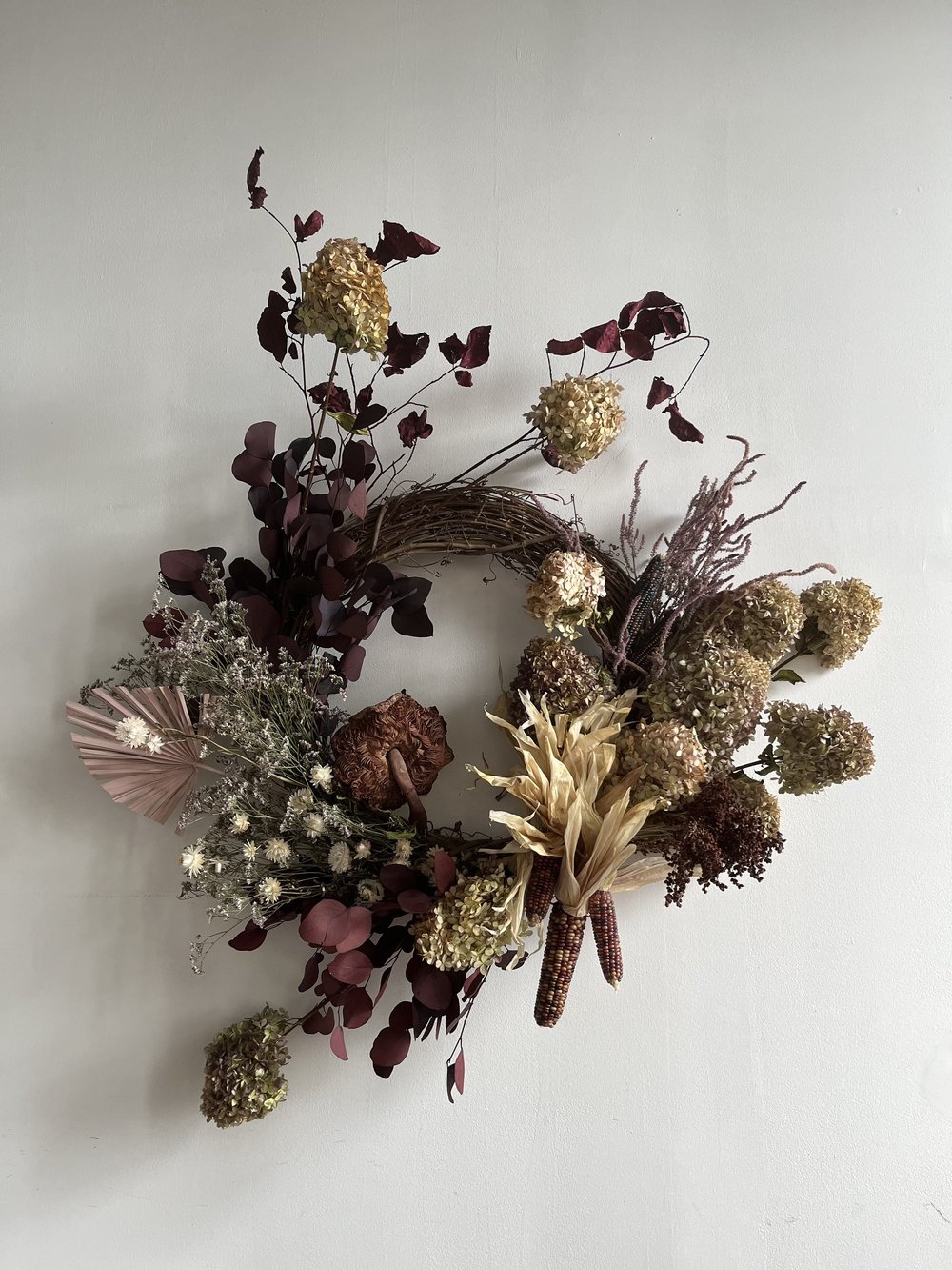Decorative wreath with dried flowers and leaves on a white background