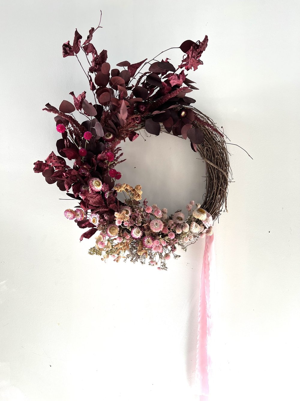 Decorative wreath with pink and purple flowers on a white background