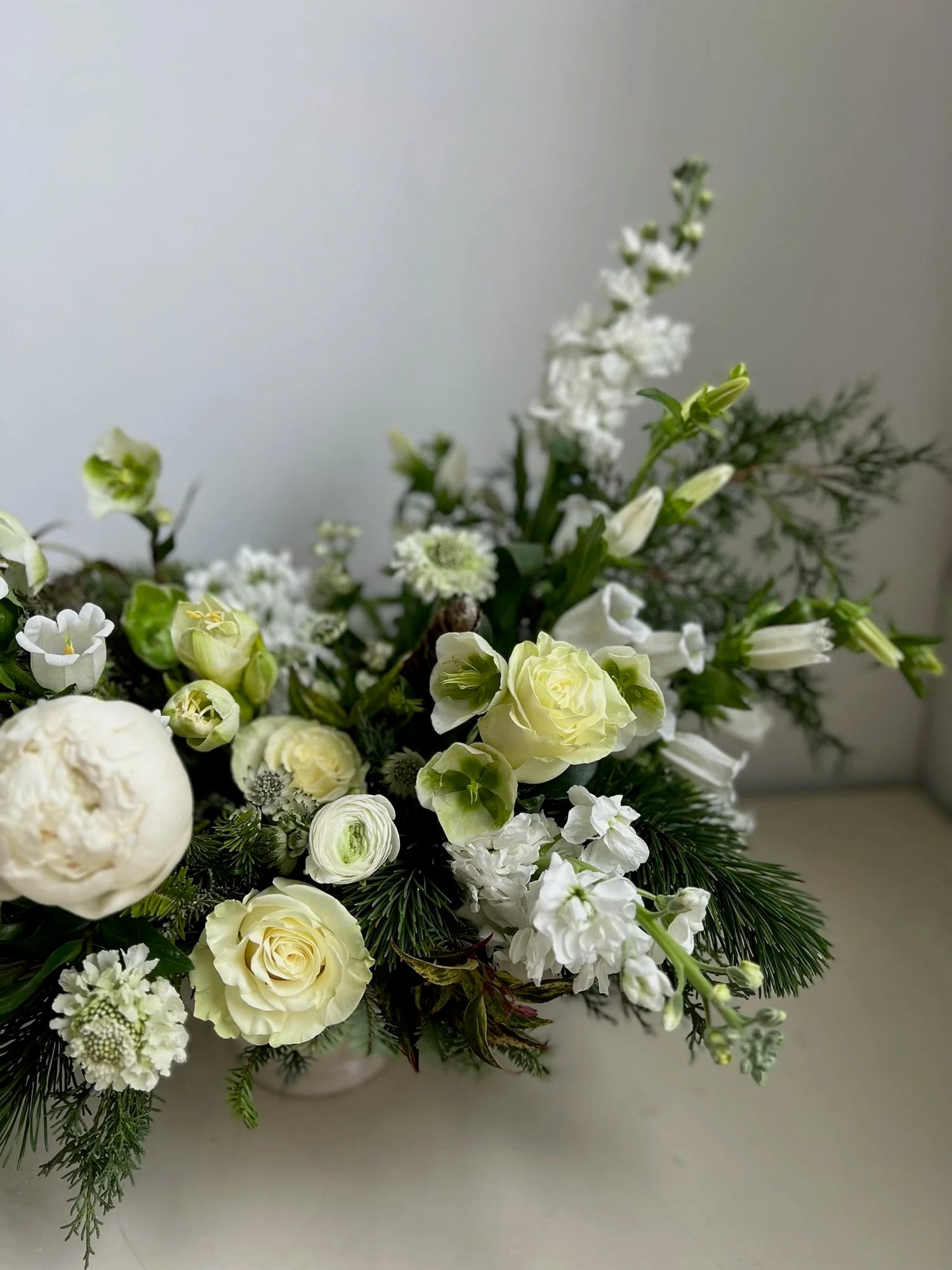 Bouquet of white and green flowers with greenery on a neutral background