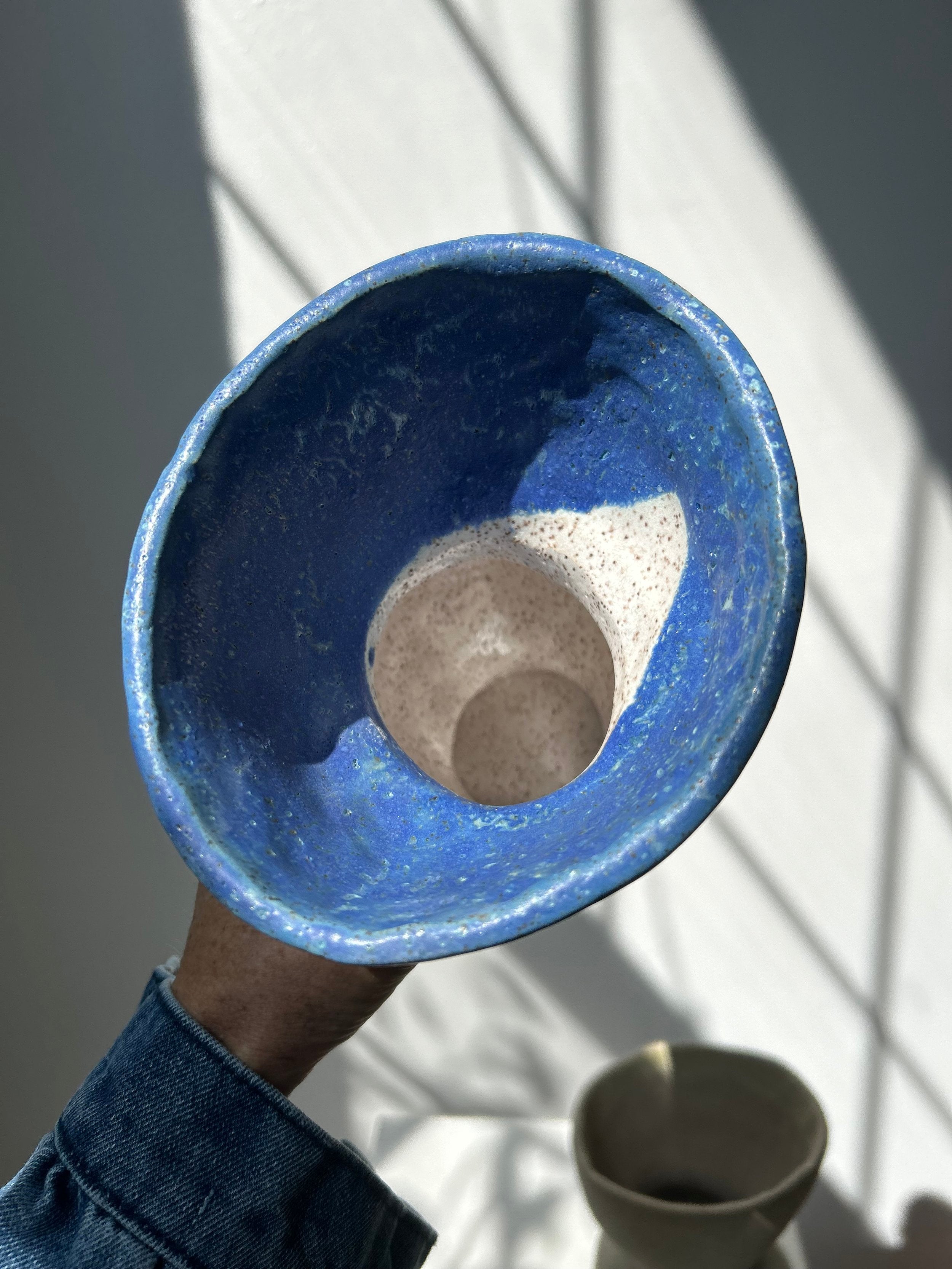Blue ceramic bowl held by a person with a white background
