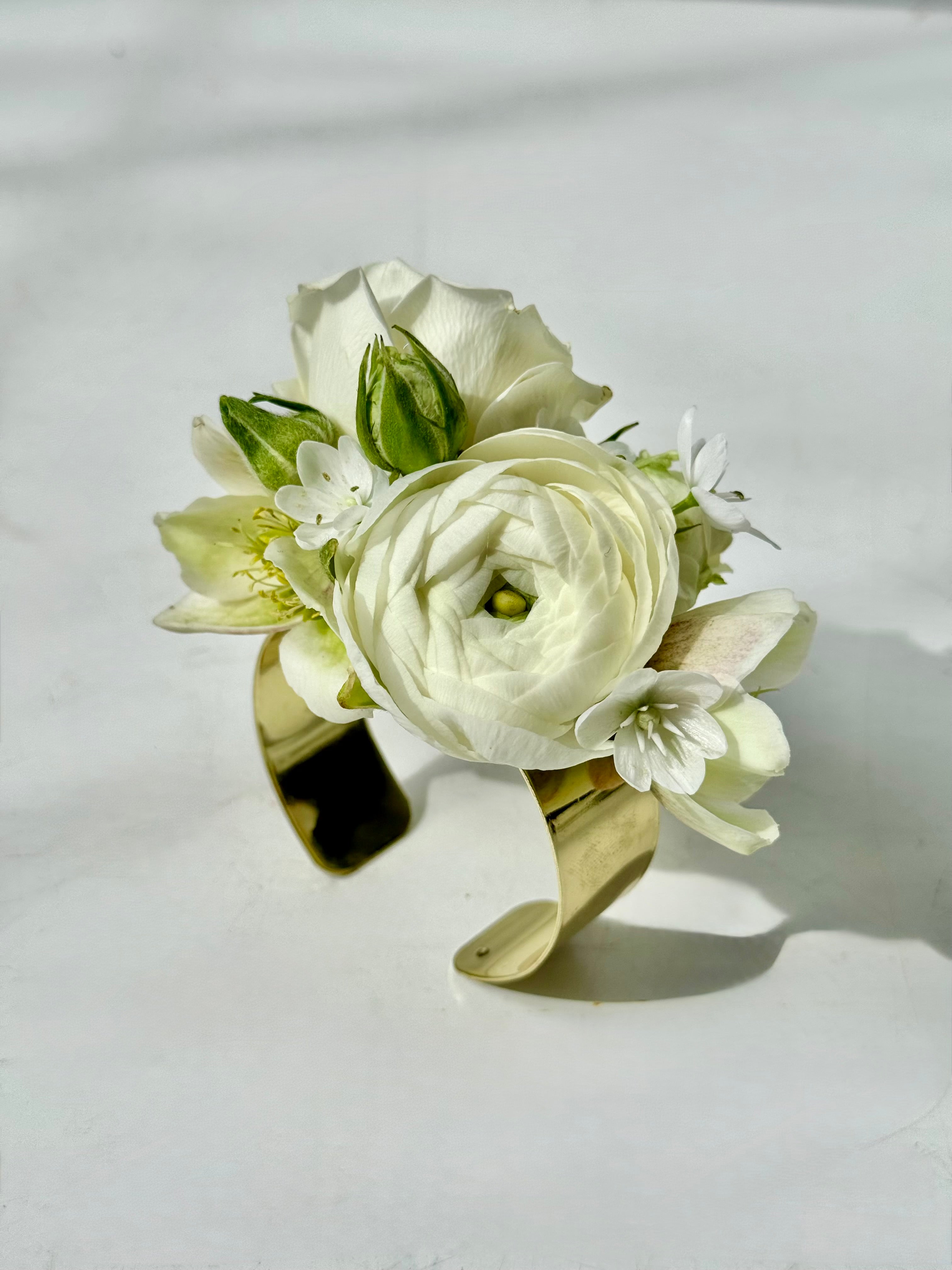Wrist corsage for maine weddings with green and white flowers- a big ranunculus and little white allium
