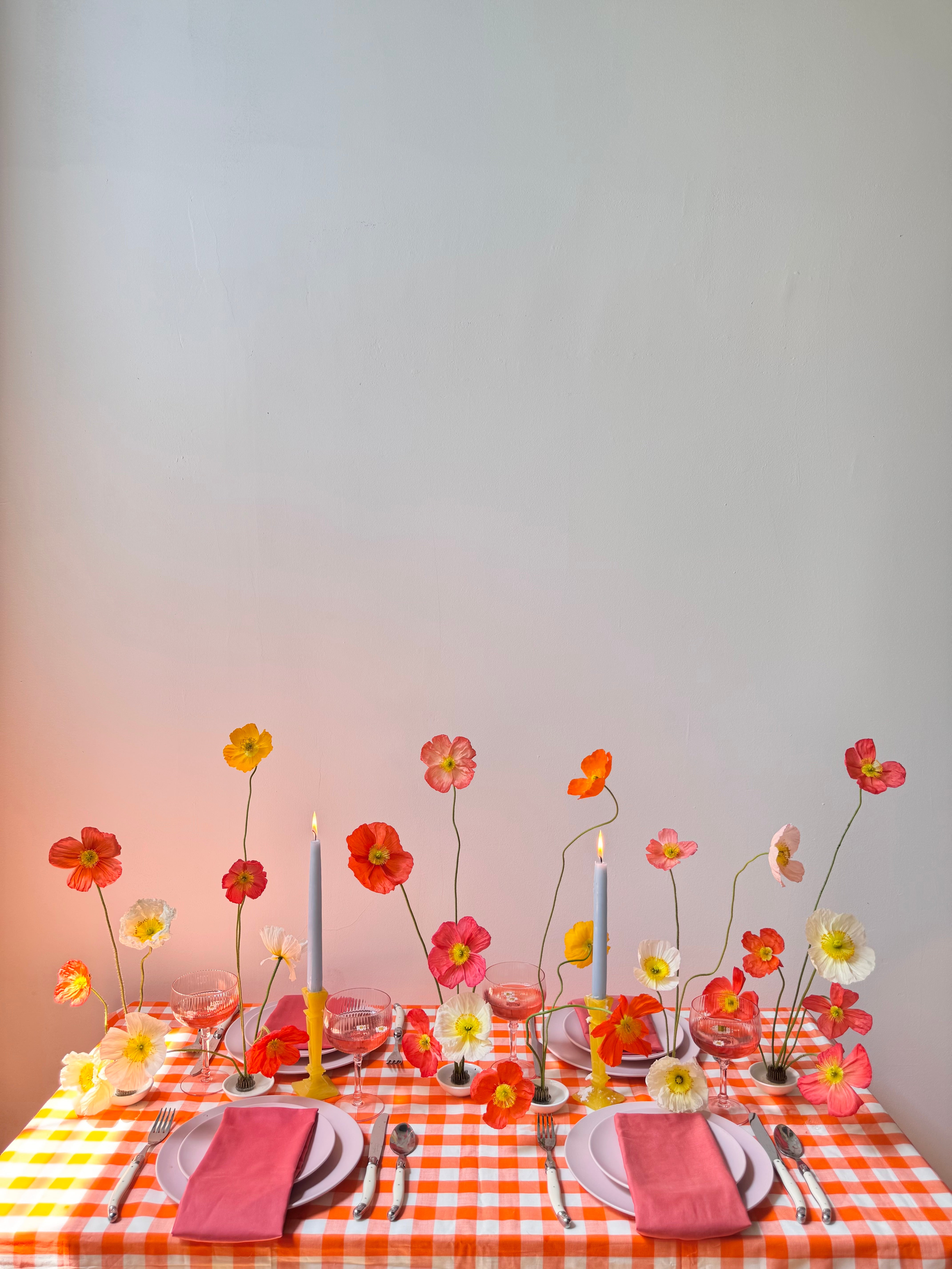 Decorative table setting with colorful flowers and checkered tablecloth.