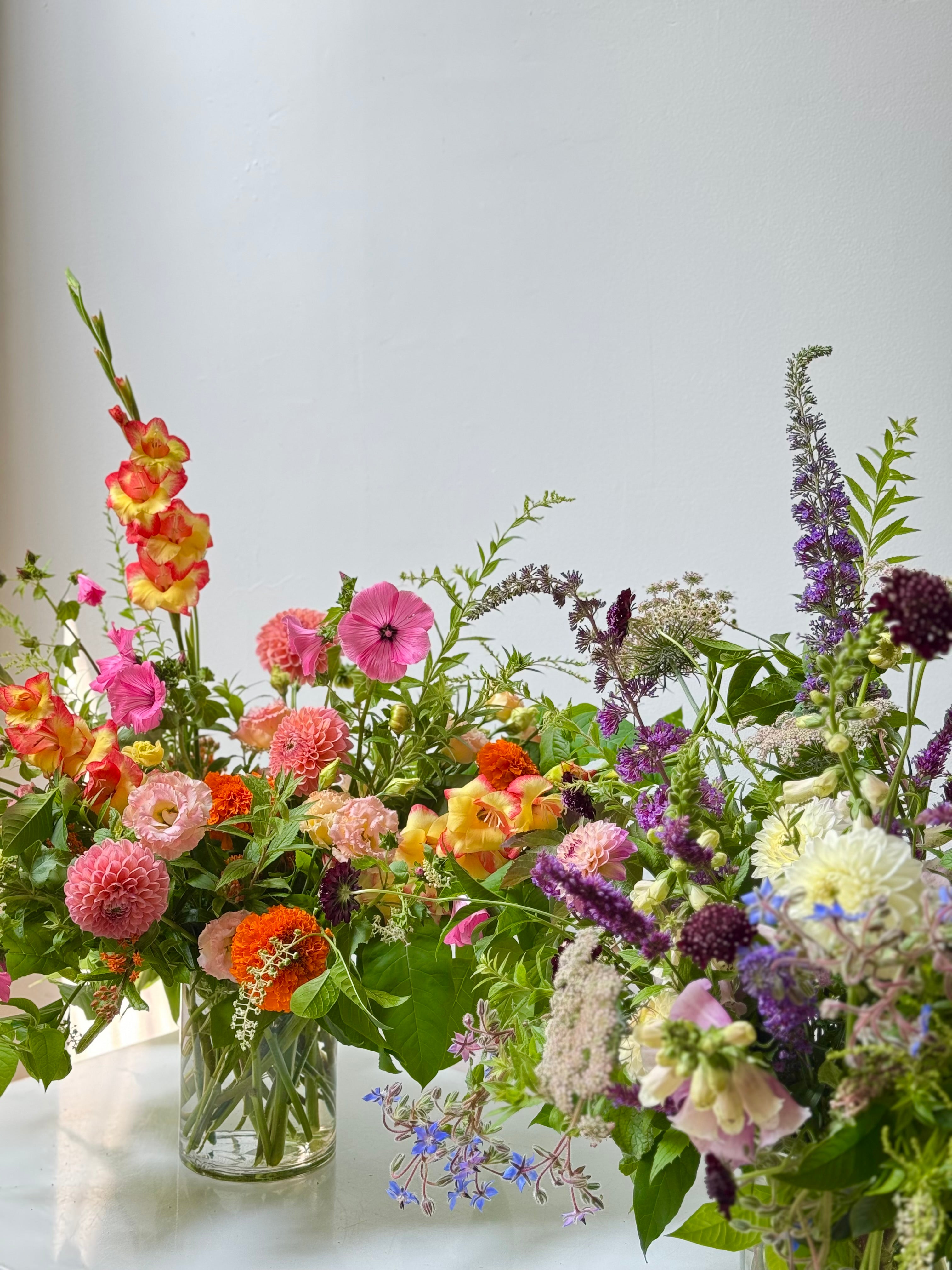 Colorful bouquet of flowers in a clear vase on a light background
