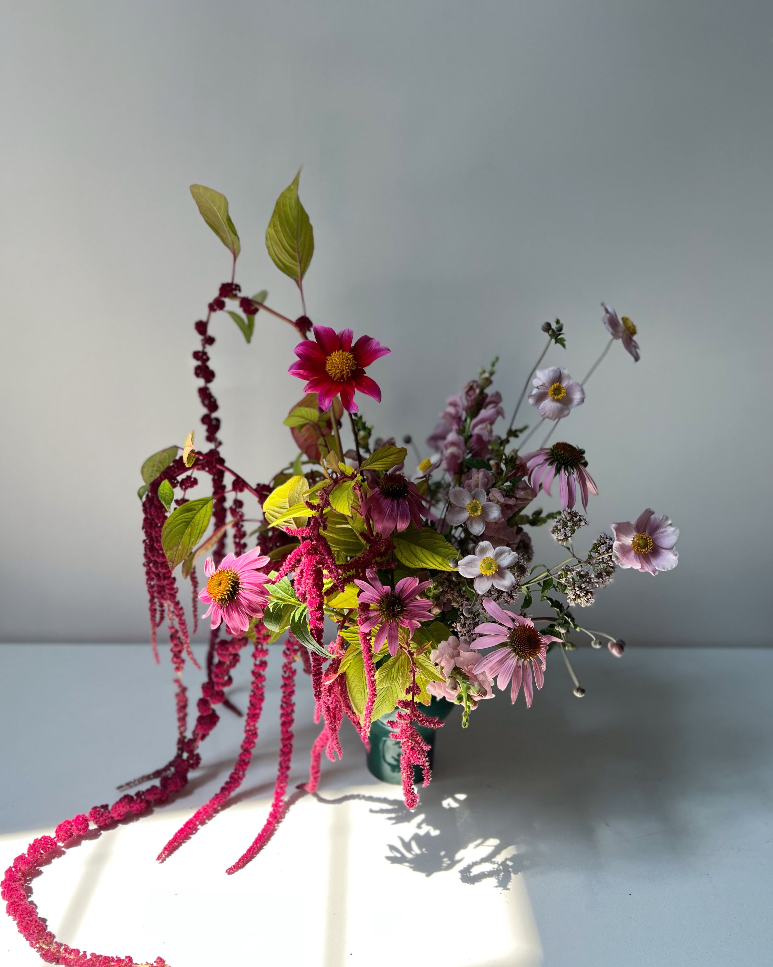 Bouquet of flowers with pink and green elements on a light gray background