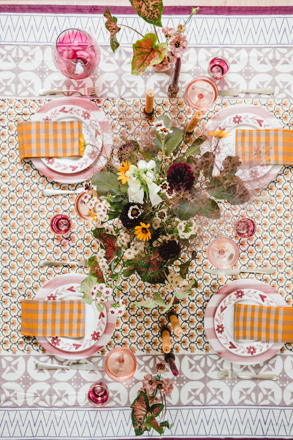 Decorative table setting with floral centerpieces, checkered napkins, and patterned tablecloth.
