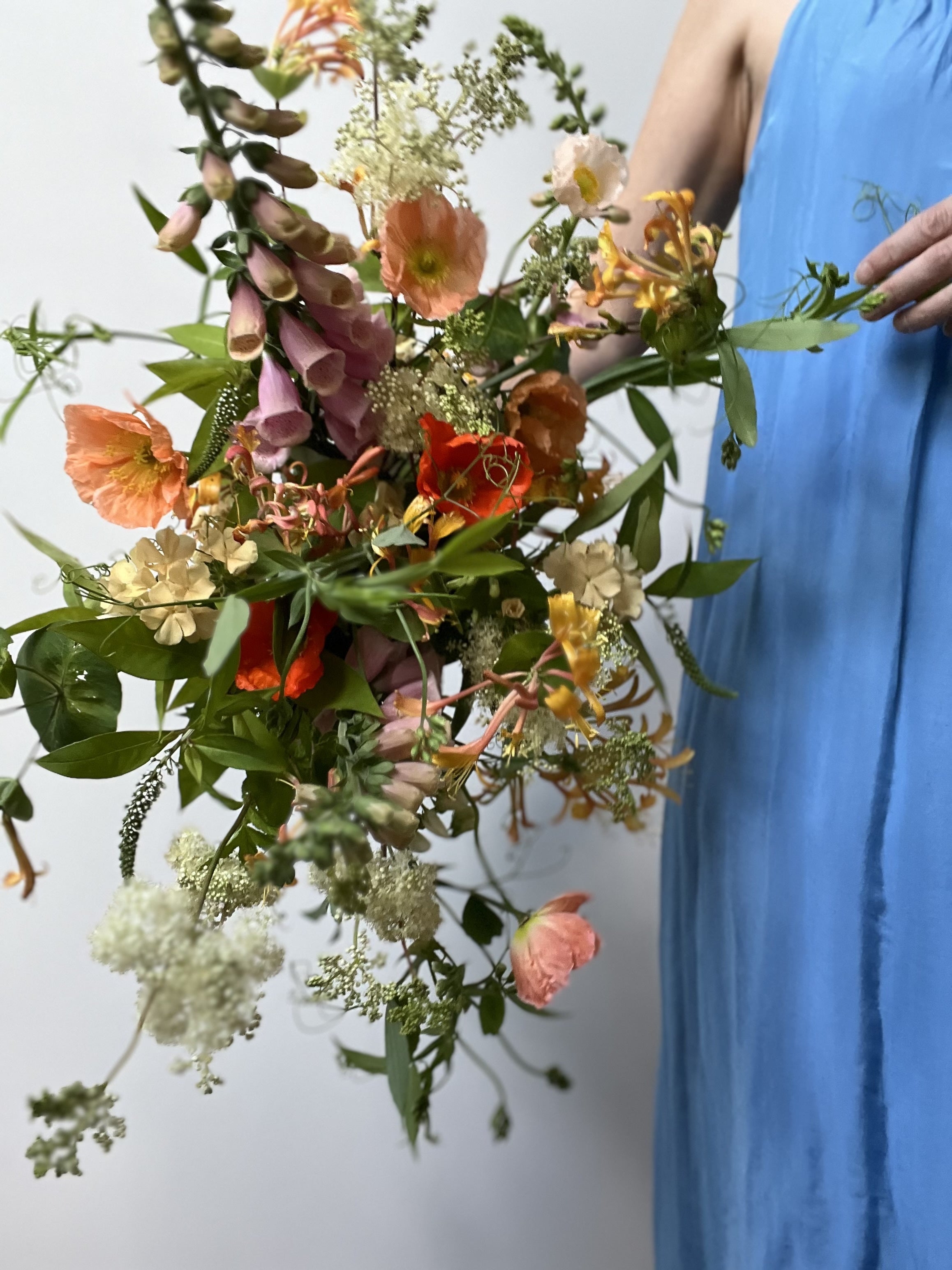Person holding a vibrant bouquet of flowers against a plain background