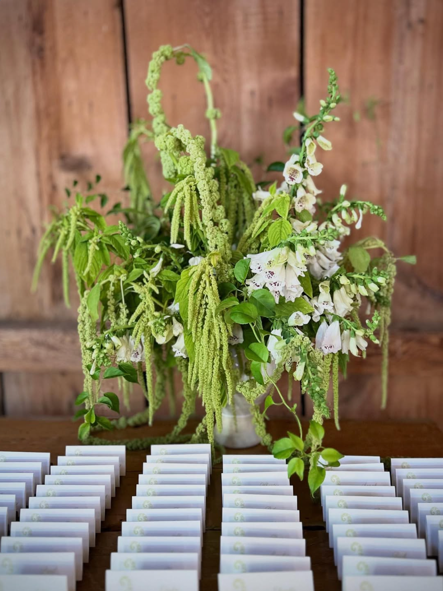 Decorative floral arrangement with greenery and white flowers on a wooden table.