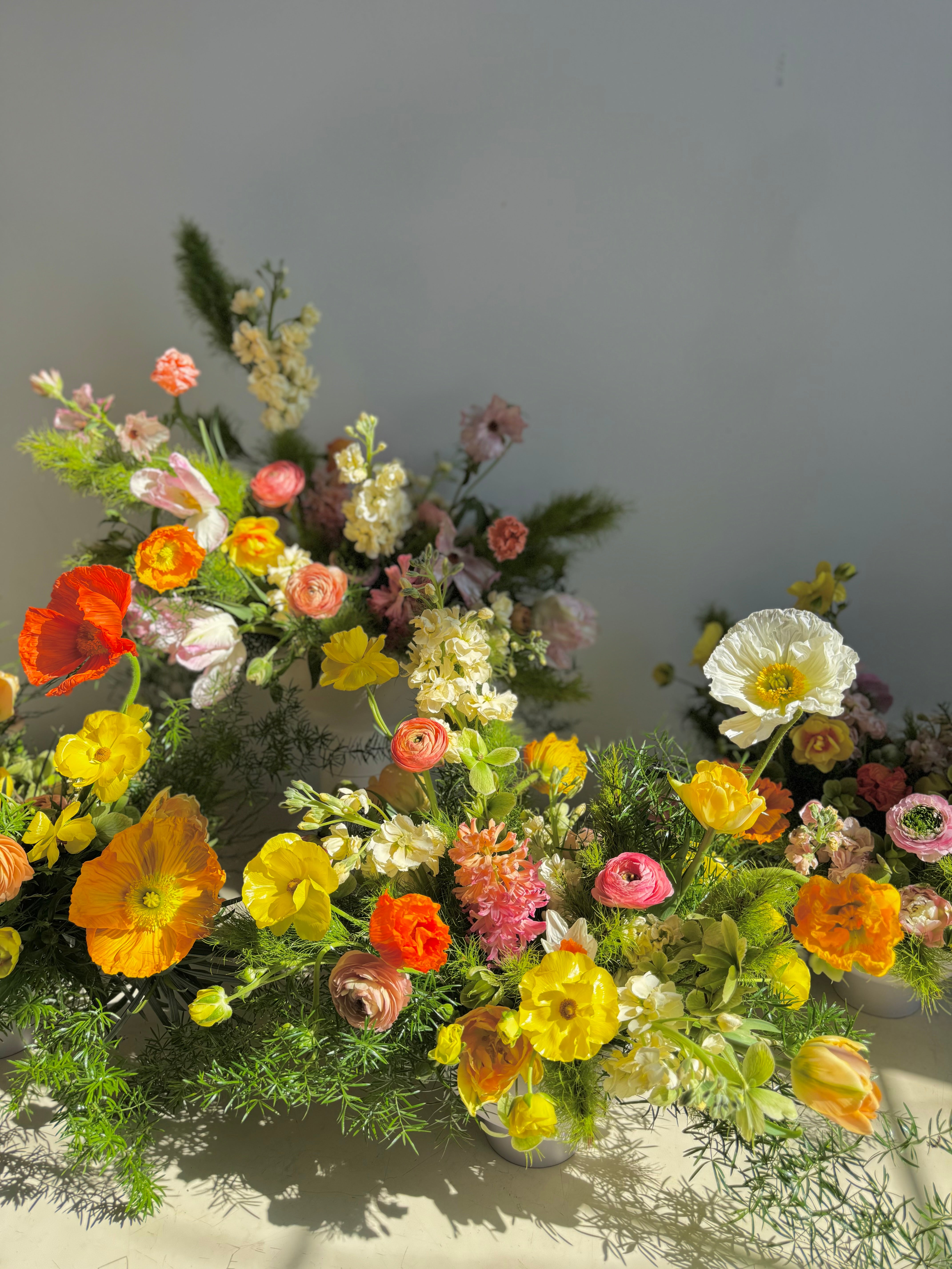 portland maine florist creates Colorful flower arrangement with various types of flowers on a neutral background including poppies and ranunculus