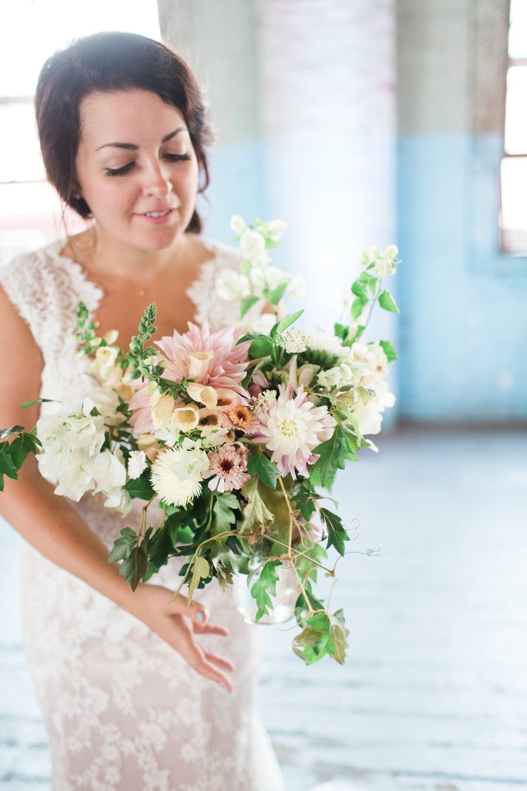 Woman in a white dress holding a bouquet of flowers indoors.