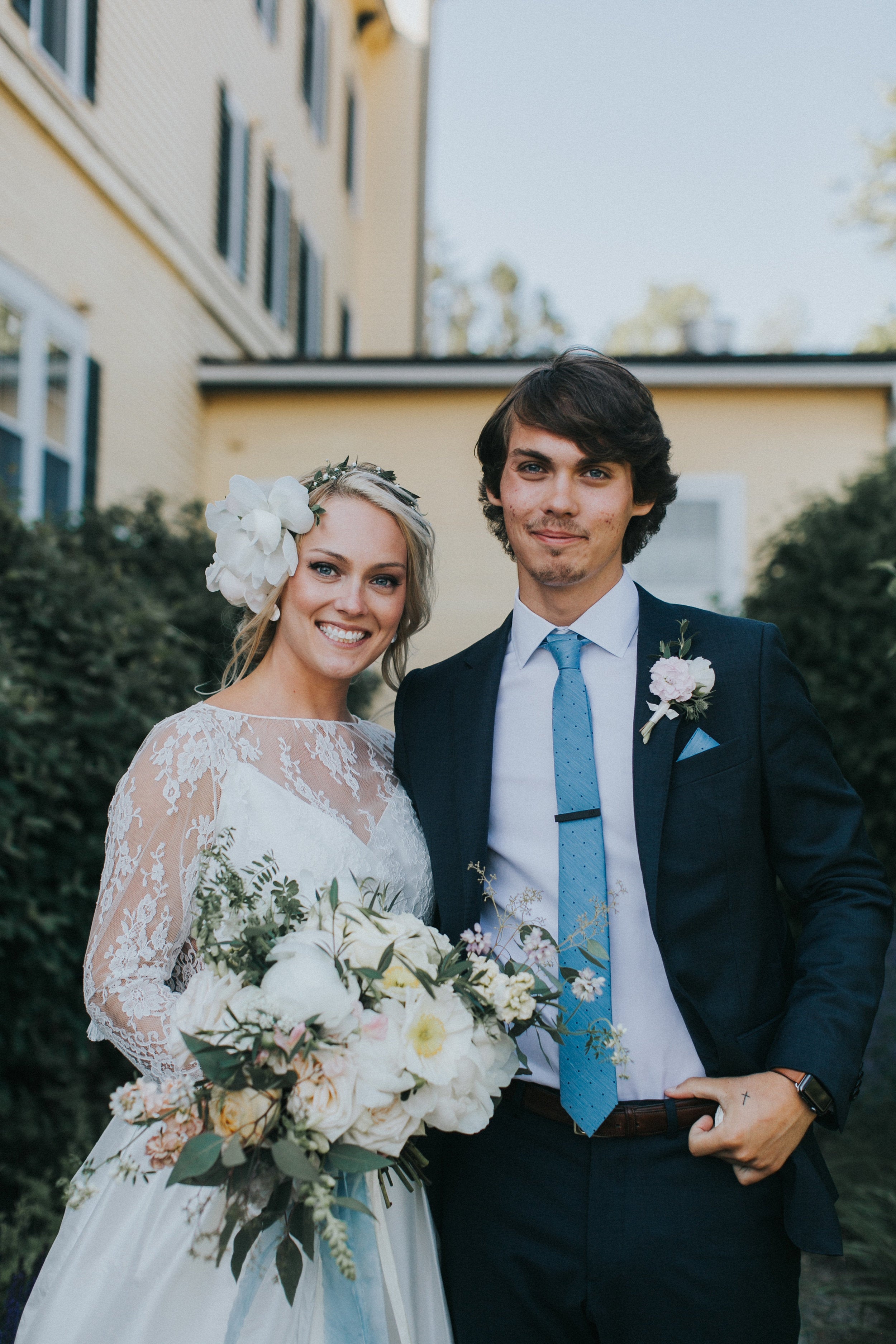 Man and woman in formal attire standing outdoors with a blurred background
