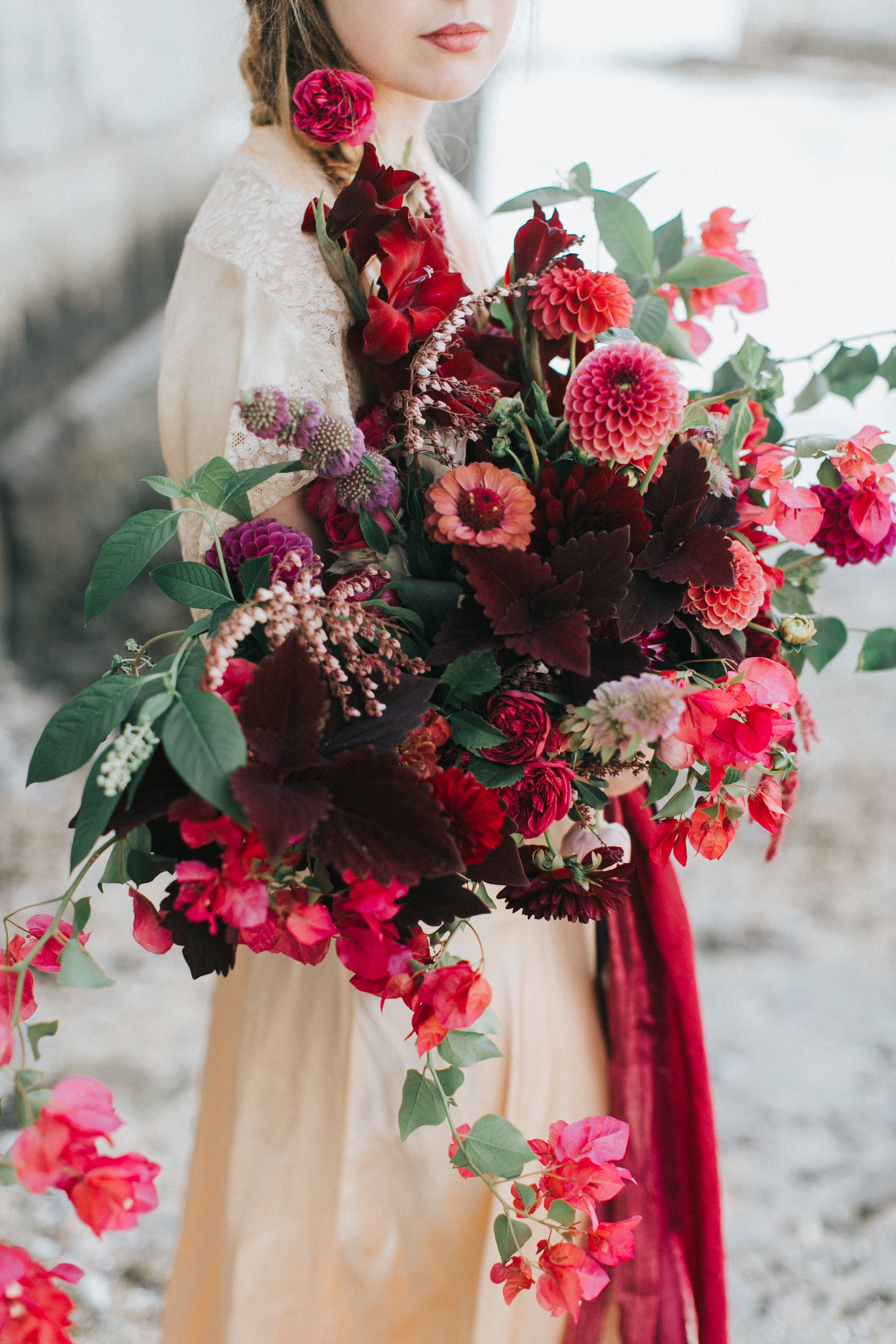 Bouquet of red and pink flowers held by a person in a snowy background