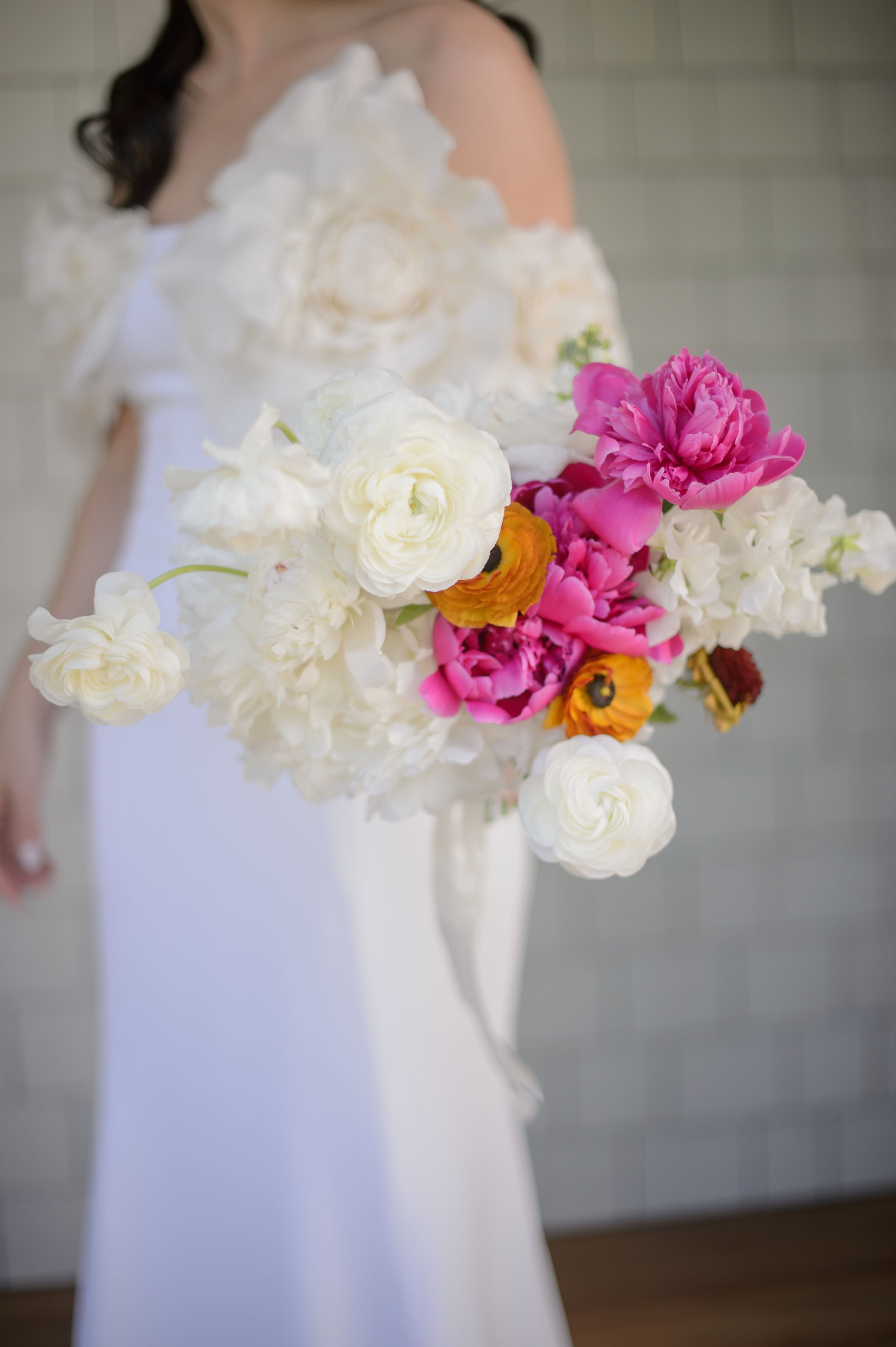 Bouquet of flowers held by a person wearing a white dress.