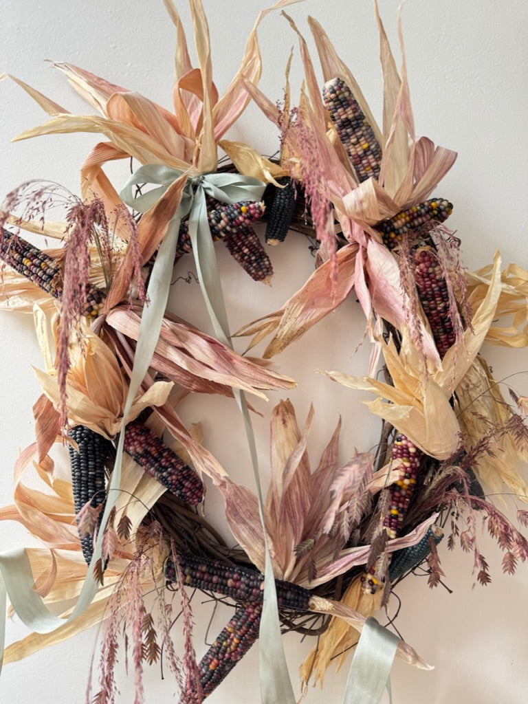 Decorative wreath with corn stalks and ribbons on a white background