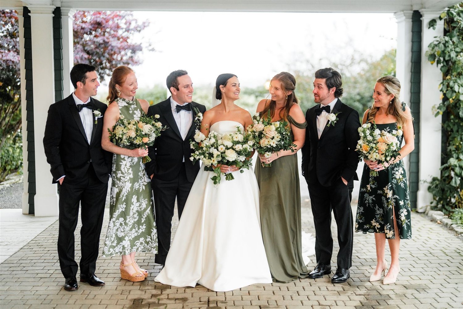 Group of people in formal attire with floral bouquets outdoors