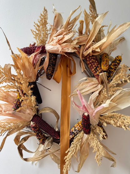 Decorative wreath with dried corn and wheat on a white background