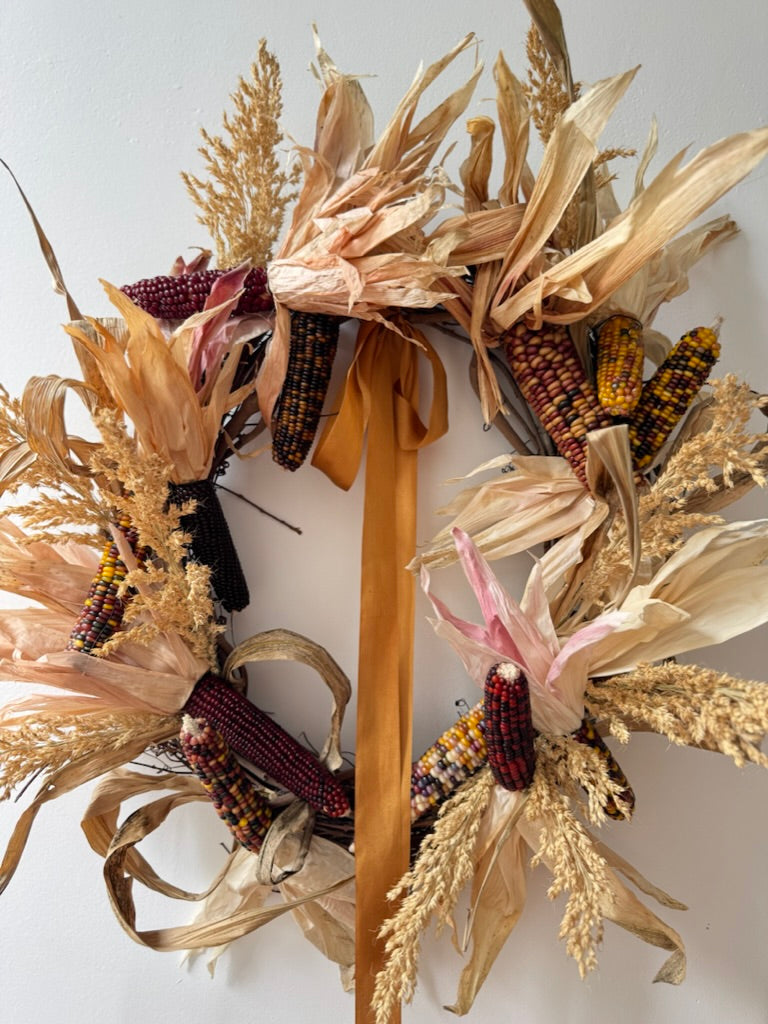 Decorative wreath with dried corn and wheat on a white background