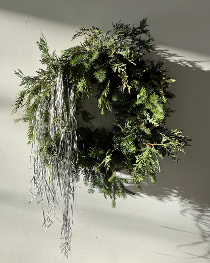 Evergreen wreath with tinsel on a white wall