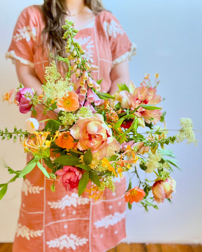 Person holding a large bouquet of flowers wearing a pink floral dress.