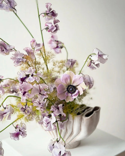 Vase with purple flowers on a white background