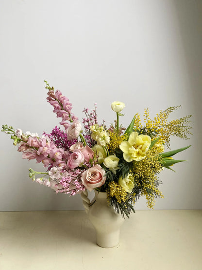 Bouquet of flowers in a white vase on a light surface with a neutral background