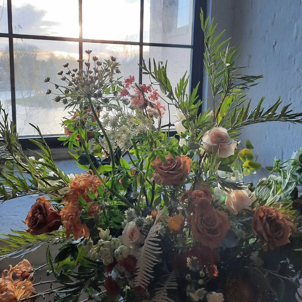 Bouquet of flowers with greenery in front of a window