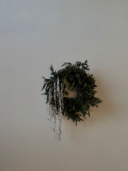 Maine evergreen wreath with hanging real metal tinsel on a plain wall