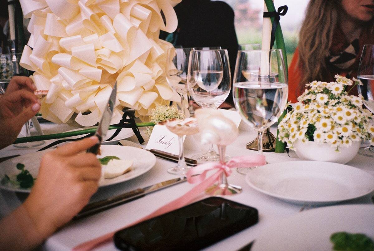 Dinner table setting with cutlery, plates, and a smartphone on a white tablecloth.