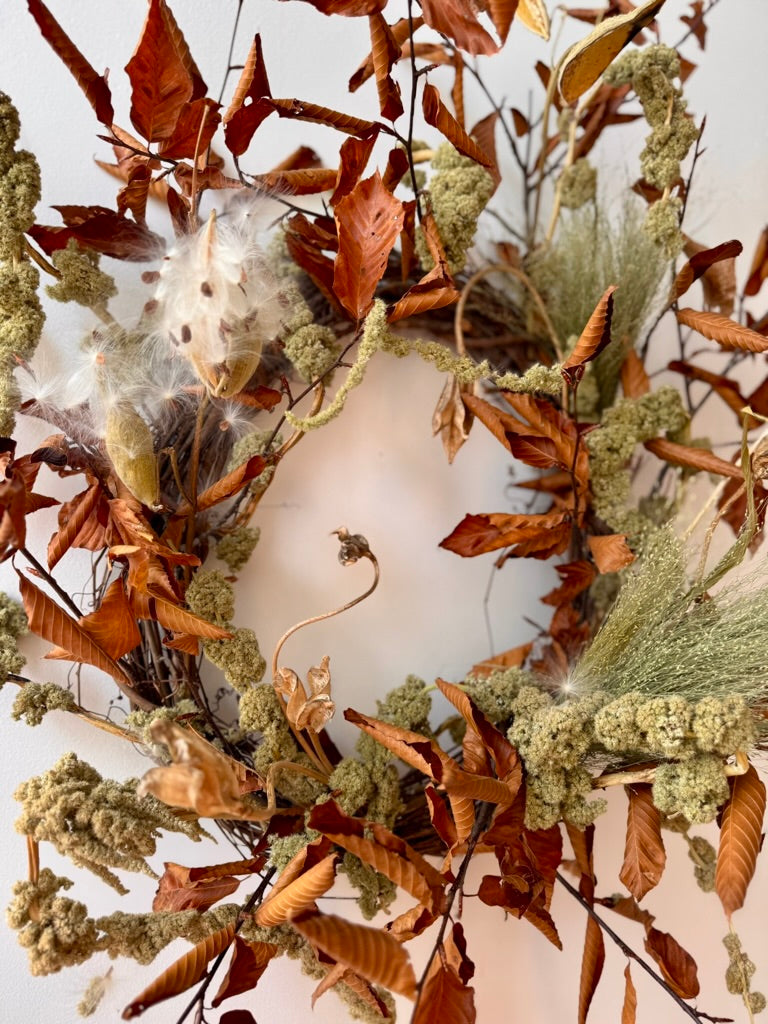 Decorative wreath with autumn leaves and branches on a white background