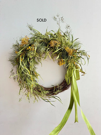 Wreath with greenery and a green ribbon on a light gray background