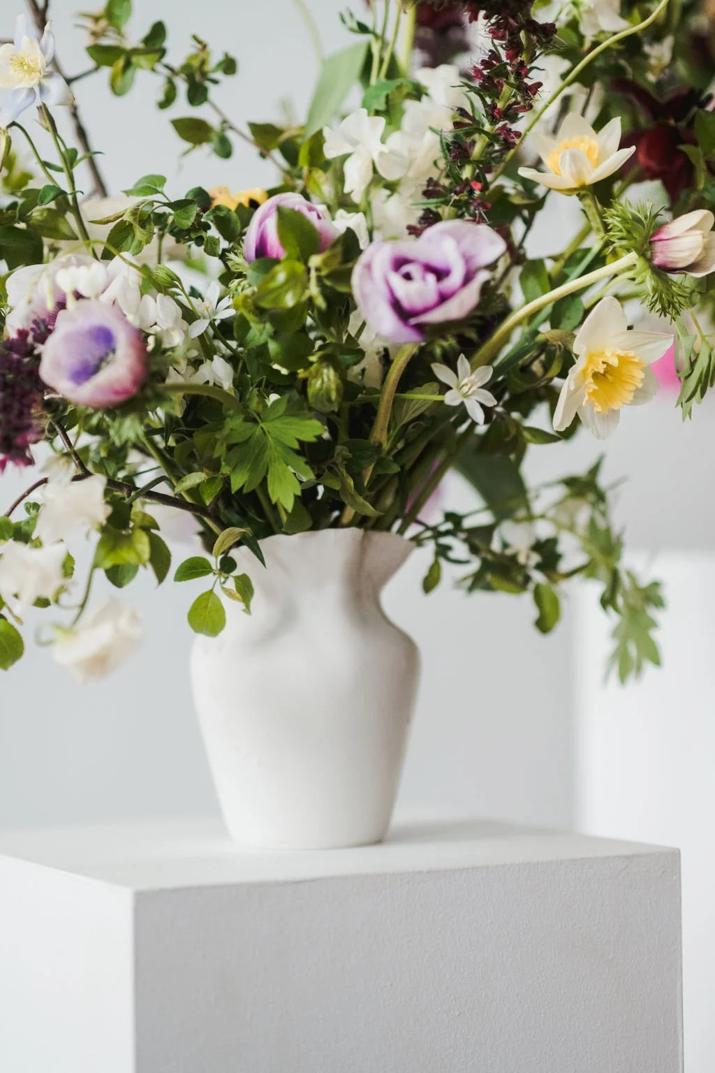 Bouquet of flowers in a white vase on a light background