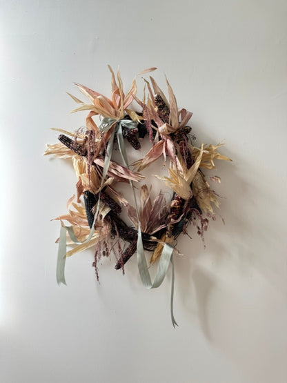 Decorative wreath with dried flowers and leaves on a plain background