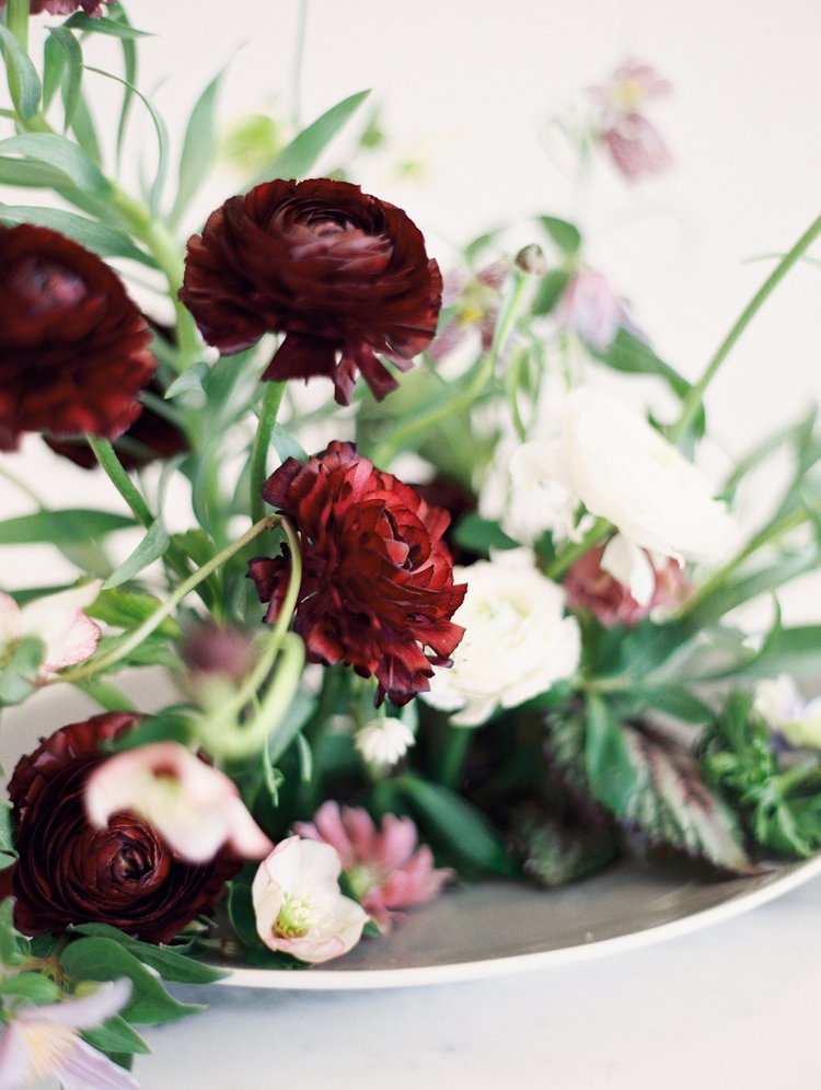 Close-up of a floral arrangement with dark red and white flowers on a light background