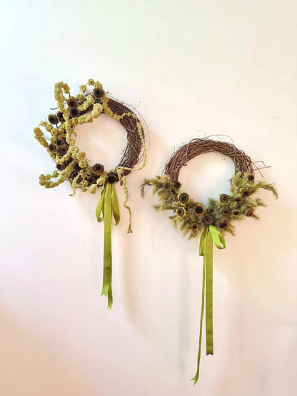 Two decorative wreaths with green ribbons on a light background