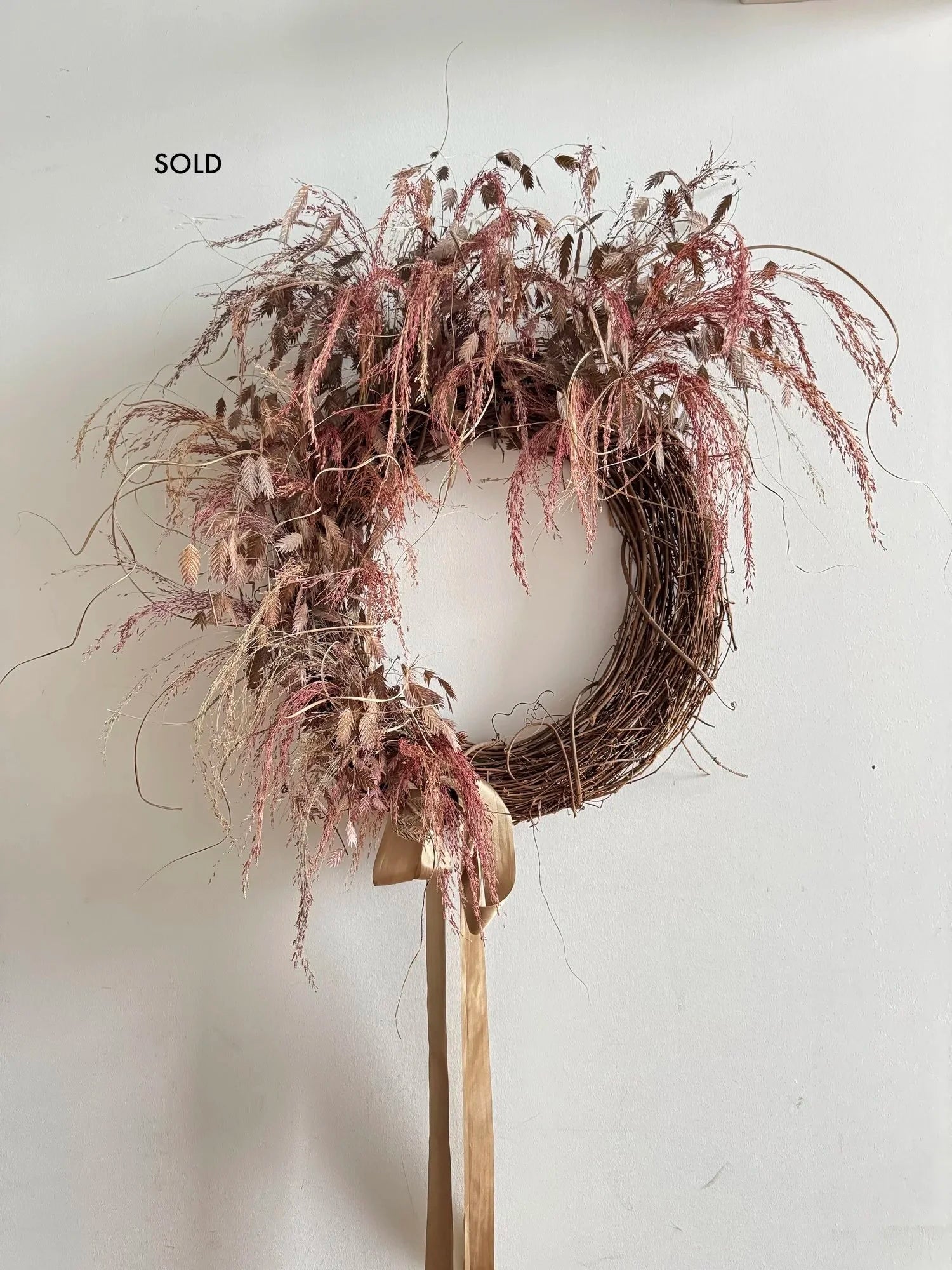 Wreath with dried flowers and ribbon on light grey background