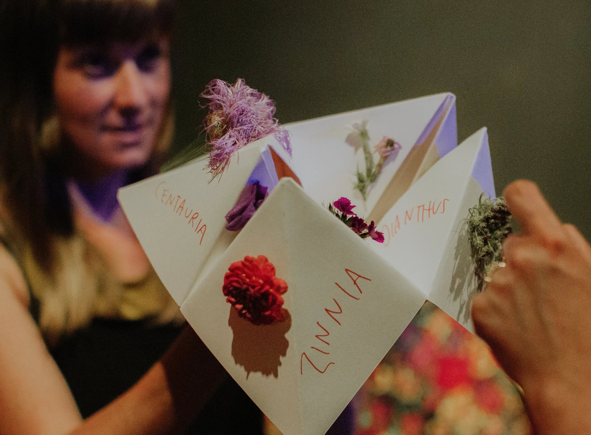 Person holding a card with floral elements and text, blurred background