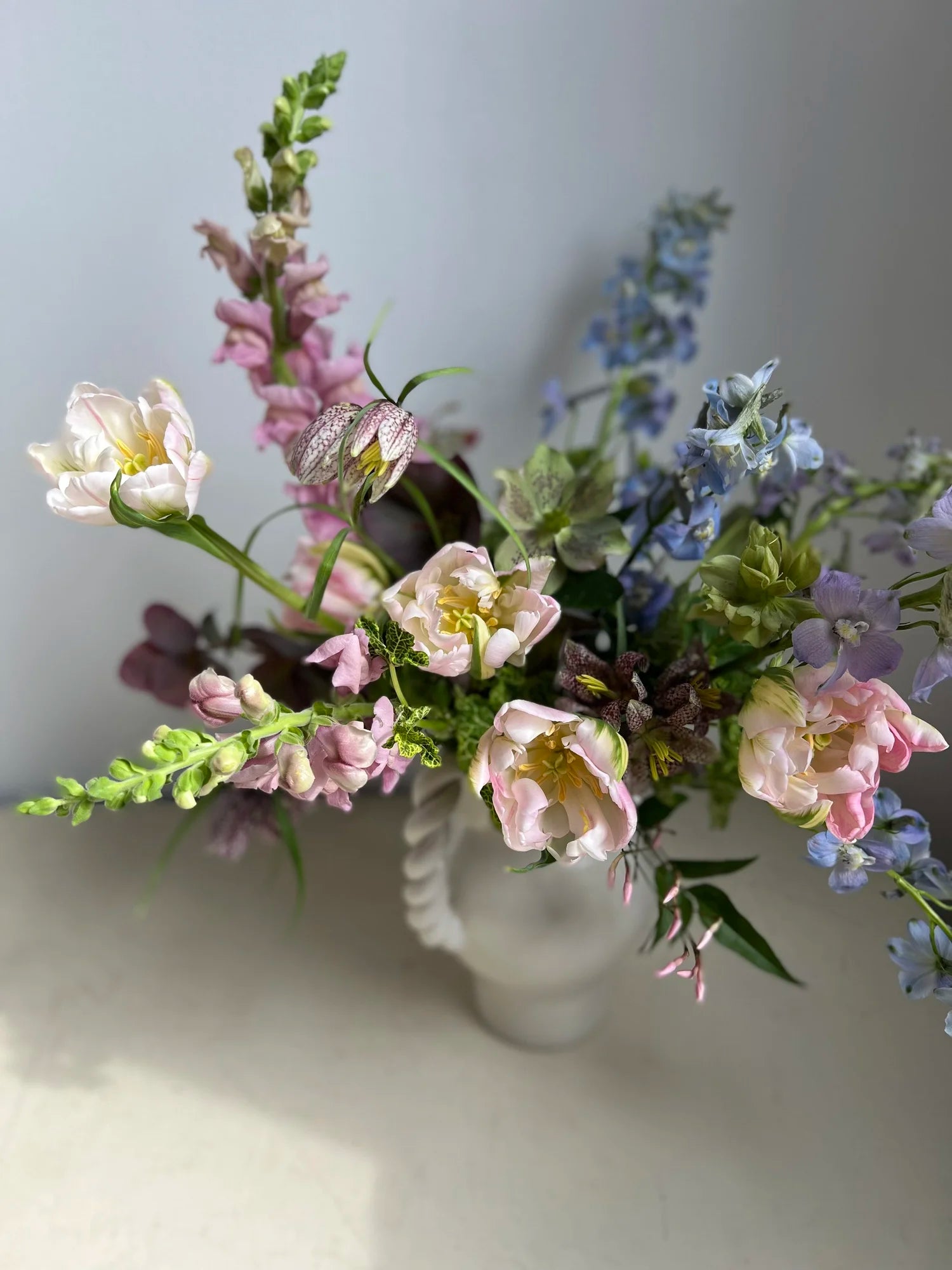 Bouquet of flowers in a clear vase on a light surface with a neutral background