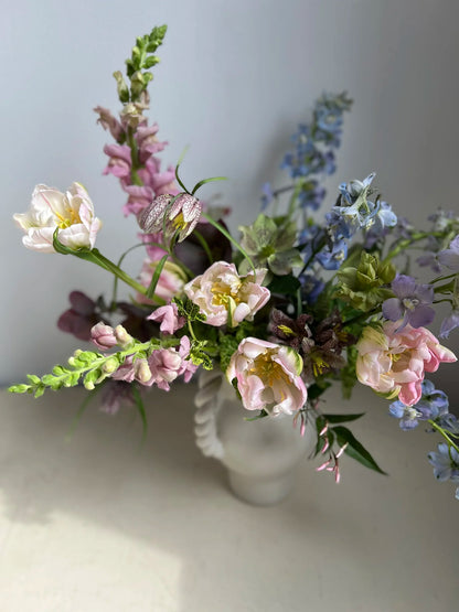 Bouquet of flowers in a clear vase on a light surface with a neutral background