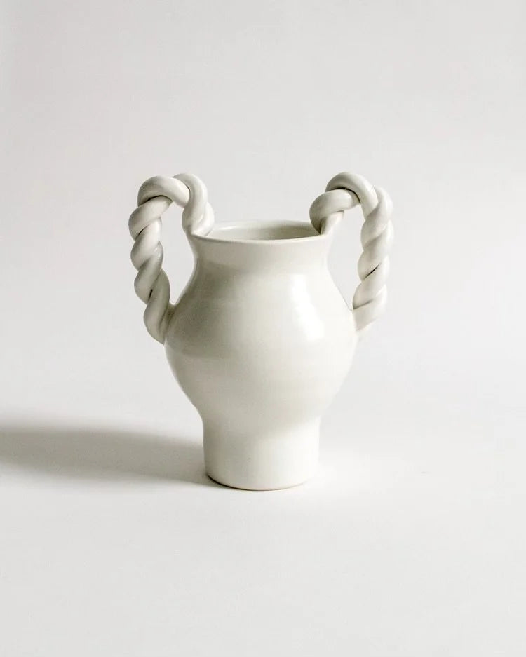 White ceramic vase with twisted handles on a light gray background