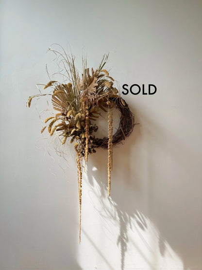 Decorative wreath with air plants on a white wall, labeled 'SOLD'.